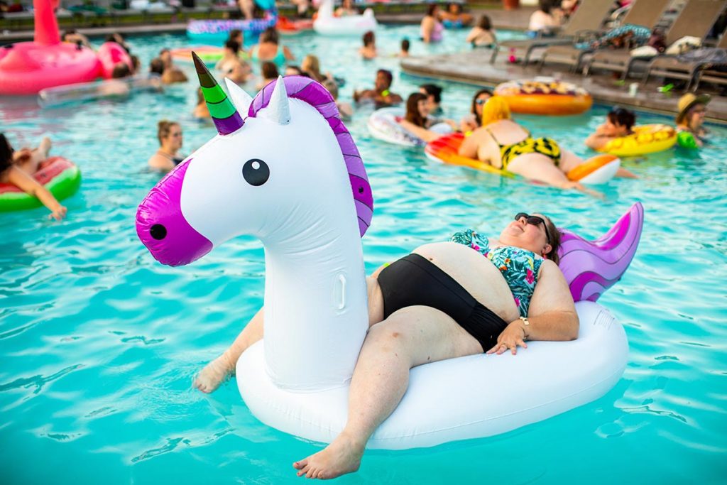 Mujer con obesidad flotando sobre un unicornio inflable en una alberca