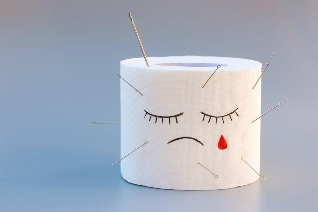 Rollo de papel de baño con una lagrima de sangre y agujas encajadas